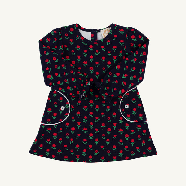The Beaufort Bonnet Company Sadie Sweatshirt Dress - Prescott Farm Flowers with Worth Avenue White is a navy blue long-sleeved dress featuring a repeating floral pattern, two front pockets with white trim, and white button accents.