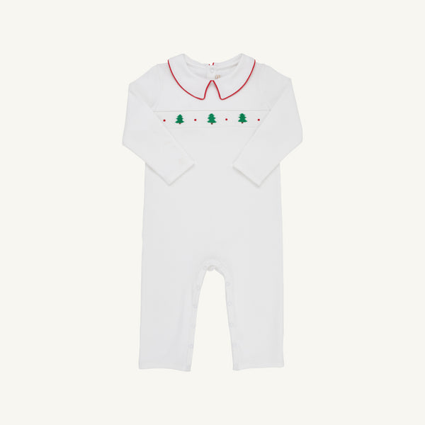 The Samuel Smocked Romper - Worth Avenue White & Richmond Red with Trees is a white long-sleeved Pima cotton romper with a red-trimmed collar and a smocked chest panel featuring green Christmas trees and red dots.