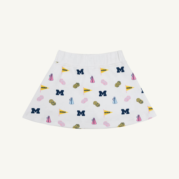 Introducing the Michigan Searcy Skort - Bold in Blue with Worth Avenue White by The Beaufort Bonnet Company, a stylish white Pima cotton skort featuring playful blue M letters, yellow flags, pink pom-poms, and megaphones for a fun school spirit and cheerleading vibe—the perfect new addition to your gameday outfit.