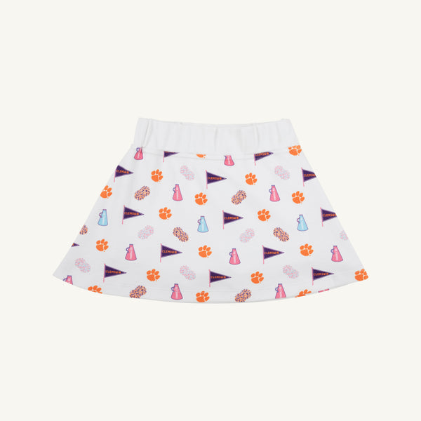 The Beaufort Bonnet Company’s Clemson Searcy Skort - Tiger Triumph with Worth Avenue White features a white, sporty skort with an elastic waistband, playfully patterned with orange paw prints, purple pennants, pink megaphones, and light blue bottles in a repeating design.