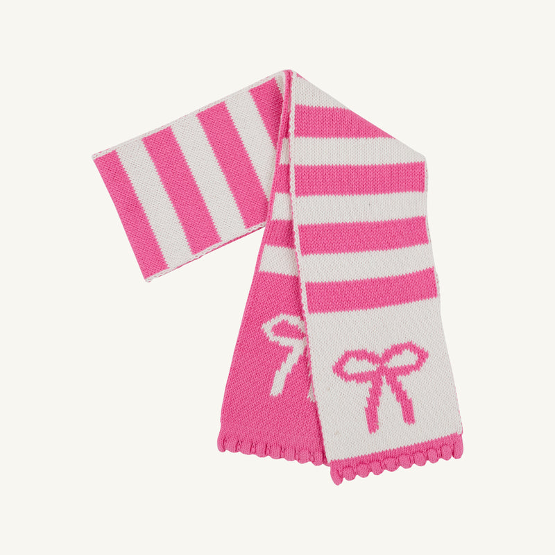 The Beaufort Bonnet Company’s Seller’s Scarf in Hamptons Hot Pink & Palmetto Pearl Stripe with Bows features alternating pink and white stripes adorned with delicate bow designs and scalloped edges. This cotton knit scarf is a cozy and stylish accessory, perfect for girls to wear on chilly days.