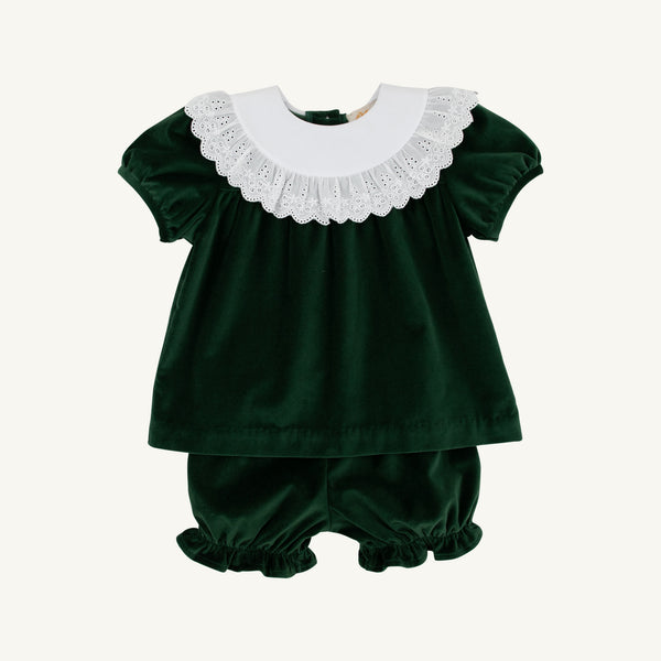 The Beaufort Bonnet Company’s Short Sleeve Bon Air Bloomer Set in Grier Green Velveteen with Worth Avenue White features a dark green velveteen baby girl outfit with short sleeves, a white scalloped lace collar, and matching bloomers with ruffled leg openings. This set is displayed against a plain, light background.