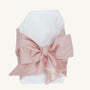 Newborn wrapped in a white Bow Swaddle ® - Southern Blush Silk, featuring a large, dusty pink bow, perfect for baby keepsake pictures.