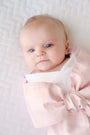 A newborn baby wrapped in a light pink Bow Swaddle ® - Southern Blush Silk, perfect for keepsake pictures.