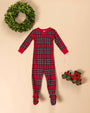 Knox’s Night Night - Society Prep Plaid red cotton footed pajamas with a zippered front, displayed next to a small wooden toy train and a boxwood wreath.