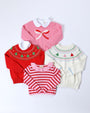 Four girls’ sweaters on a white background: Isabelle’s Intarsia Sweater - Hamptons Hot Pink with Scalloped Bow, a red Christmas tree sweater, a white multicolored tree sweater, and a red and pink striped sweater.