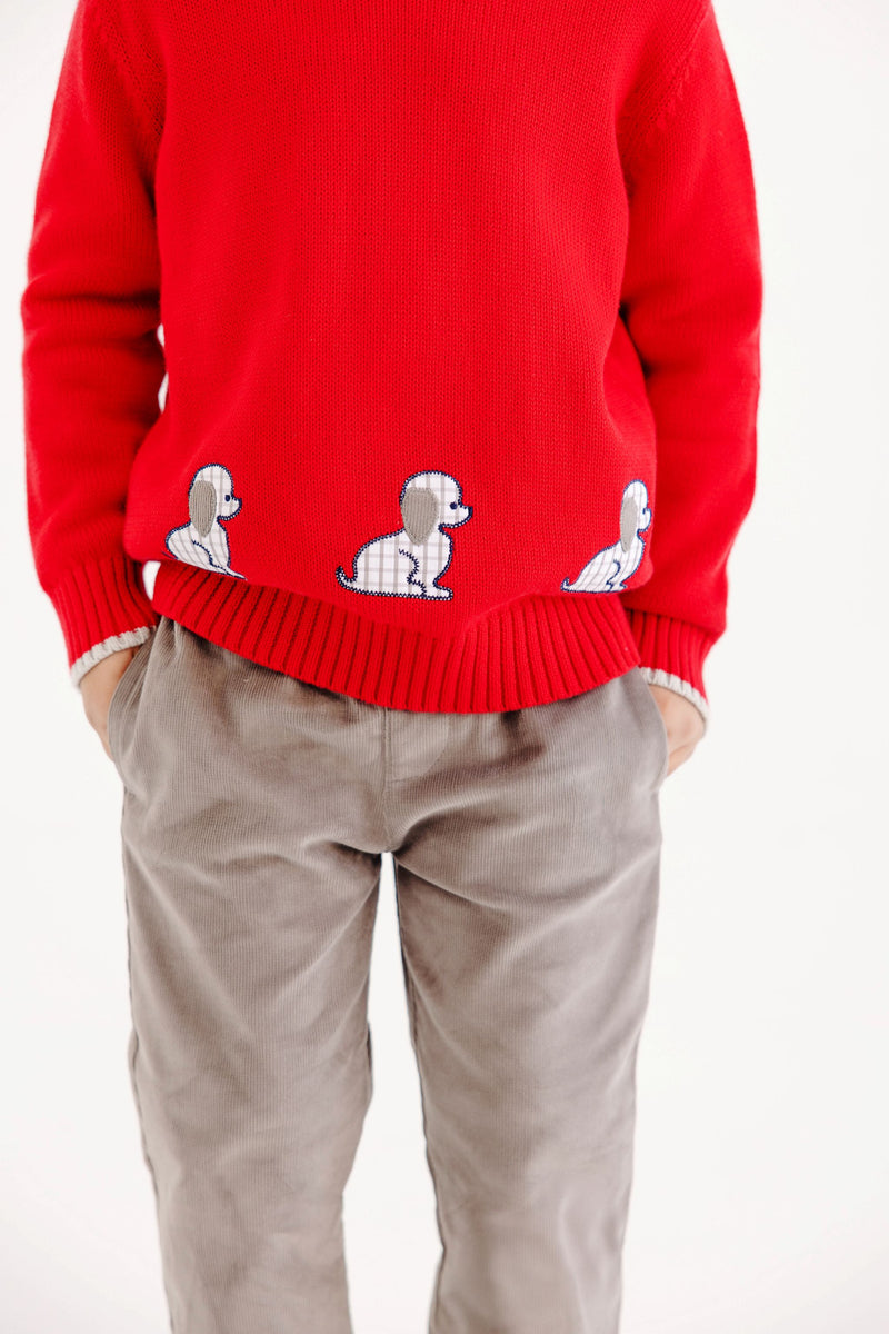 Red long-sleeved Isaac’s Intarsia Sweater - Richmond Red with Grantley Gray and Dogs featuring a row of three small puppy motifs along the hem, worn with gray pants.
