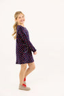 A young girl smiles wearing a navy blue Sadie Sweatshirt Dress - Prescott Farm Flowers with Worth Avenue White, featuring a small red floral print and a side pocket.