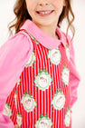 A girl wearing a Maude’s Peter Pan Collar Shirt (Long Sleeve Pima) - Hamptons Hot Pink under a red and white striped jumper featuring a repeating pattern of dogs in circular frames.