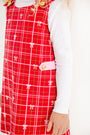 A young child wearing The Beaufort Bonnet Company’s Janie Jumper in Torrington Tartan with Pier Party Pink, layered over a long-sleeved white shirt, standing against a white background.