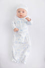 A baby dressed in The Beaufort Bonnet Company’s Sir Proper’s Sweet Arrival (Beale Street Blue) Bundle – a charming everyday set complete with a white hat, matching bib, and light blue layette gown – lies contentedly on a white background, gazing up with wide-eyed wonder. This adorable scene captures the perfect baby shower gift.