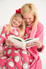 A woman and a young girl read a book together while wearing matching Payton Pajama Set - Distinguished Doggies with Hamptons Hot Pink cotton pajamas featuring dog prints.