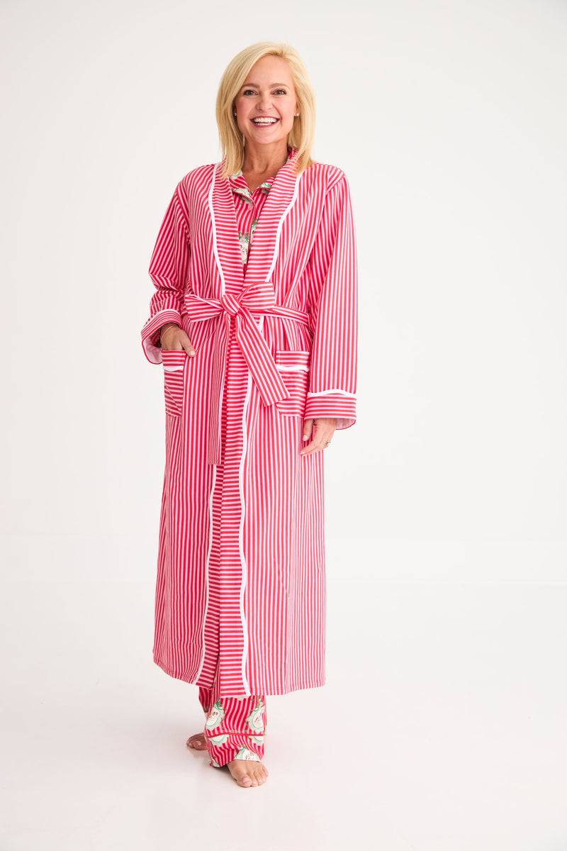 A smiling woman wears a cozy Rest Awhile Robe - Richmond Red & Hamptons Hot Pink in red and white stripes with white piping over matching pajama pants.