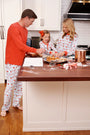 A family, dressed in matching pajamas, bakes cookies together in the kitchen, smiling and savoring the moment. The counter is scattered with baking ingredients and cookie cutters as everyone relaxes in the cozy comfort of The Beaufort Bonnet Company’s Men’s Sunday Style Sweatpants - Santa’s Laundry Line, perfect for Christmas loungewear.