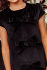 A child wearing The Beaufort Bonnet Company’s Betts Bow Dress - Newport Night Velveteen, a short-sleeved velveteen dress featuring three large velvet bows on the front. Only the lower face, shoulders, and upper body are visible.
