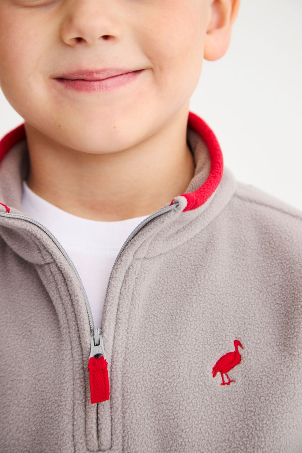 Close-up of a cozy gray Hayword Half-Zip (Fleece) - Grantley Gray with Richmond Red, featuring a red inner collar, red zipper pull, and a small red bird logo on the chest.
