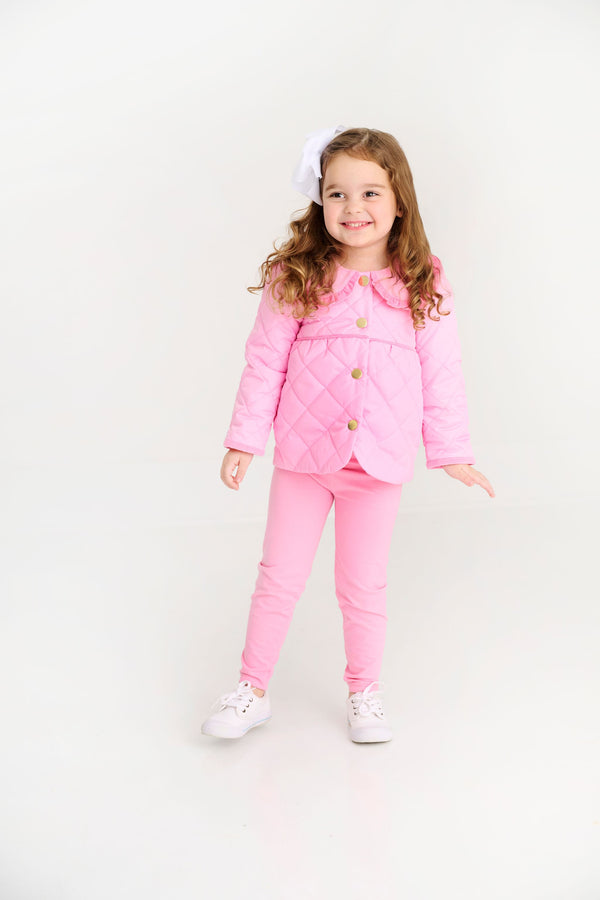A young girl wears a bright, hot pink Maude’s Carlyle Quilted Coat - Hamptons Hot Pink with Palm Beach Pink, featuring a rounded collar and matching pants.