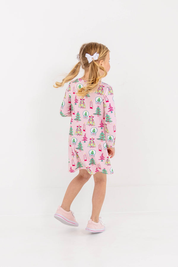 A young girl wearing a Long Sleeve Polly Play Dress - Christmas Coloring Contest, a long-sleeve Pima cotton dress printed with festive snow globes and trees.