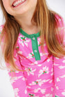 Child wearing the Sara Jane’s Sweet Dream Set - Bows of Holly with Kiawah Kelly Green by The Beaufort Bonnet Company, shown from the shoulders down; features festive pink fabric with white holiday bow prints and green trim—part of our holiday family matching pajamas collection.