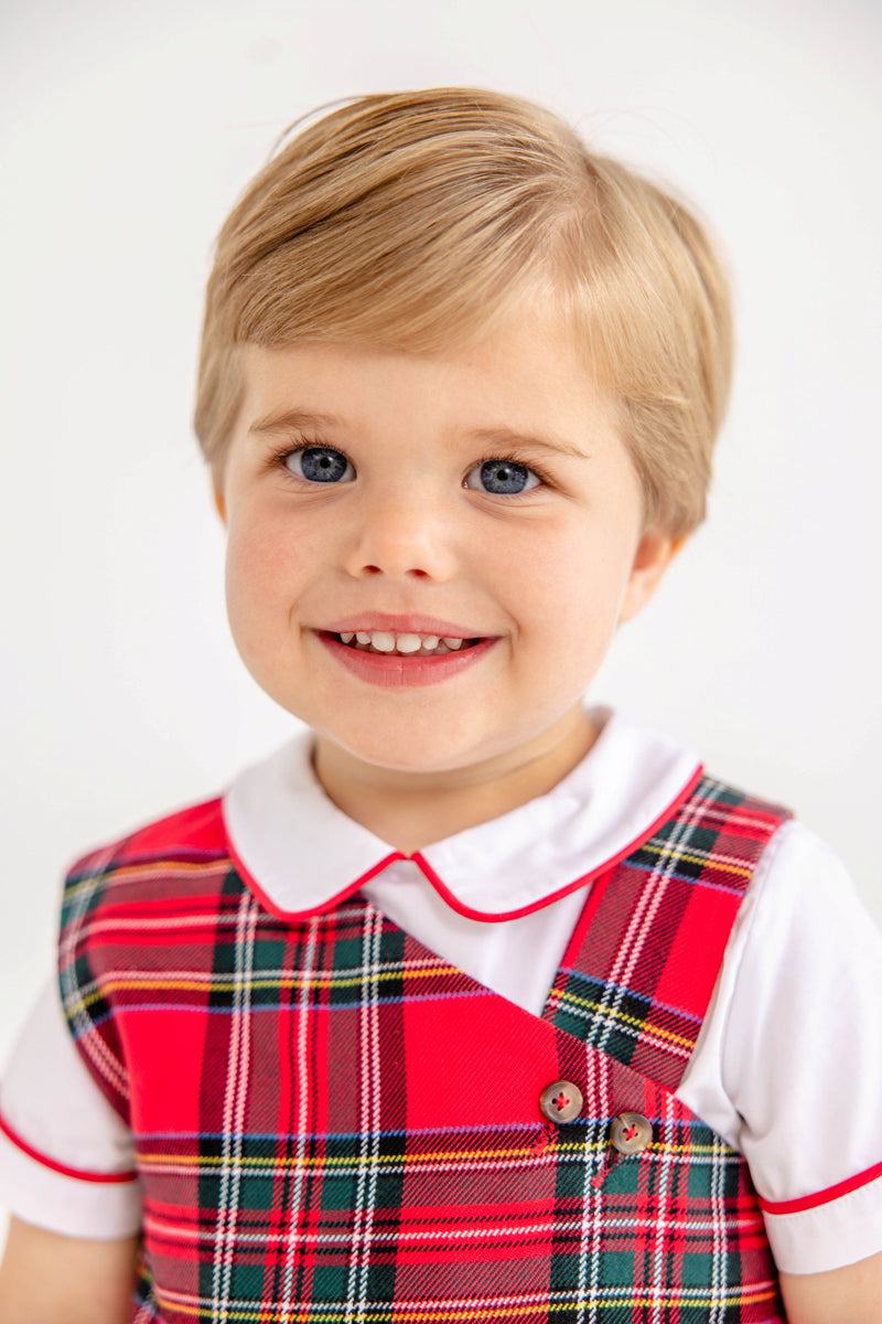 A young child smiles while wearing a white shirt with a Peter Pan collar under a Barr Clay Bubble - Society Prep Plaid with Worth Avenue White & Richmond Red.