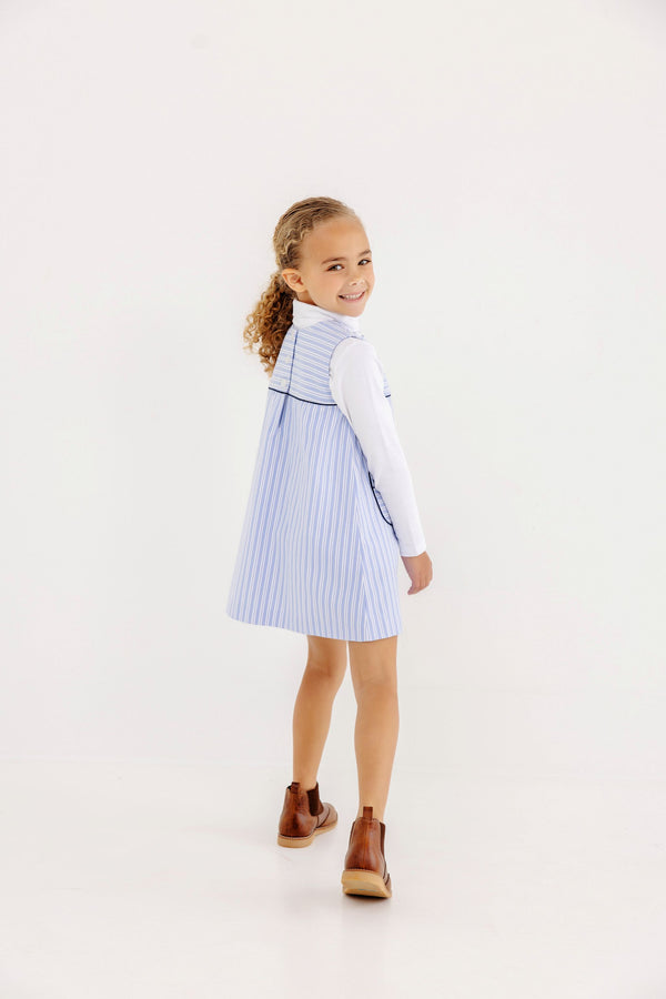 A girl wearing a Jill Jumper - Park City Periwinkle Stripe with Nantucket Navy over a long-sleeved white shirt and brown boots.
