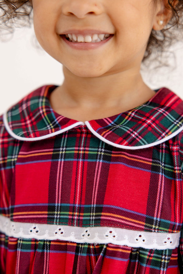 A smiling child wears a Goldie Locks Nightgown - Society Prep Plaid with Worth Avenue White, featuring a white-trimmed Peter Pan collar and white lace trim at the waist.