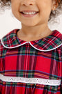 A smiling child wears a Goldie Locks Nightgown - Society Prep Plaid with Worth Avenue White, featuring a white-trimmed Peter Pan collar and white lace trim at the waist.
