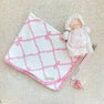 A small stuffed doll wearing a white bonnet and dress, attached to a Parker Paci Clip - Pink Greenbrier Gingham with Palm Beach Pink and a pink baby pacifier.