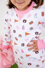 A young child wears The Beaufort Bonnet Company’s Auburn Cassidy Comfy Crewneck – Tiger Thrill with Hamptons Hot Pink, featuring Auburn University-themed designs like logos, flags, and pom-poms. Smiling slightly to show school spirit, the child holds pink pom-poms and stands with one hand on their hip.