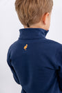 A child with short light brown hair faces away from the camera, wearing The Beaufort Bonnet Company’s Auburn Hayword Half-Zip in Auburn Blue with Auburn Orange—a perfect layering piece for game day.