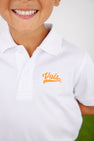 A smiling child wears The Beaufort Bonnet Company’s Tennessee Prim & Proper Polo in Worth Avenue White, crafted from soft Pima Cotton Knit and adorned with an orange script embroidered Tennessee logo on the chest. The image is cropped to display only the lower half of the face and upper torso.