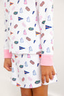 A child is shown from the torso down, wearing The Beaufort Bonnet Company’s Florida Searcy Skort in the colorful Florida Forever print with Worth Avenue White. Only one hand and part of the skort are visible against a plain background.