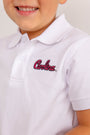 A child smiles while wearing The Beaufort Bonnet Company’s South Carolina Prim & Proper Polo in Worth Avenue White, featuring “Carolina” embroidered in red on the chest.