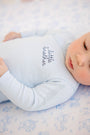 A baby wearing the Cameron Cross Front Set in Buckhead Blue with Nantucket Navy Little Brother, a light blue Pima cotton long-sleeve shirt embroidered with the words little brother in navy script.