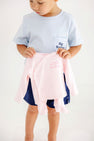 A young child wearing a Buckhead Blue with Nantucket Navy Big Brother Carter Crewneck holds up a pale pink long-sleeved infant onesie embroidered with little sister.
