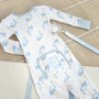 A long-sleeved blue heron print baby romper with a monogrammed front pocket, paired with a Parker Paci Clip - Blue Grand Gasparilla Gingham with Buckhead Blue on a blue and white checkered ribbon.