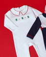 Samuel Smocked Romper - Worth Avenue White & Richmond Red with Trees: a white Pima cotton infant romper with a red-trimmed collar and a smocked chest panel featuring a row of small green embroidered trees.