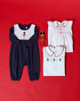 A Long Sleeve Bradford Romper - Nantucket Navy & Worth Avenue White with Soldier Embroidery, a white sleeveless dress with red buttons and holly embroidery, a white shirt with green tree embroidery, and a toy soldier ornament on a red background.