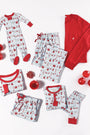 Knox’s Night Night - Santa’s Laundry Line by The Beaufort Bonnet Company features matching family Christmas pajamas in red and light blue with festive prints, including a cozy holiday onesie option, arranged flat with red ornaments and a gift box on a white background.