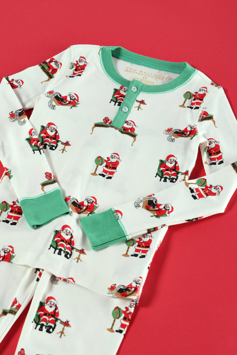Sutton’s Sweet Dream Set - Serious Santa Business by The Beaufort Bonnet Company features playful Santa Claus and reindeer illustrations on a red background, complete with festive green cuffs and buttons, all crafted in cozy Pima cotton for the perfect Christmas pajama set.