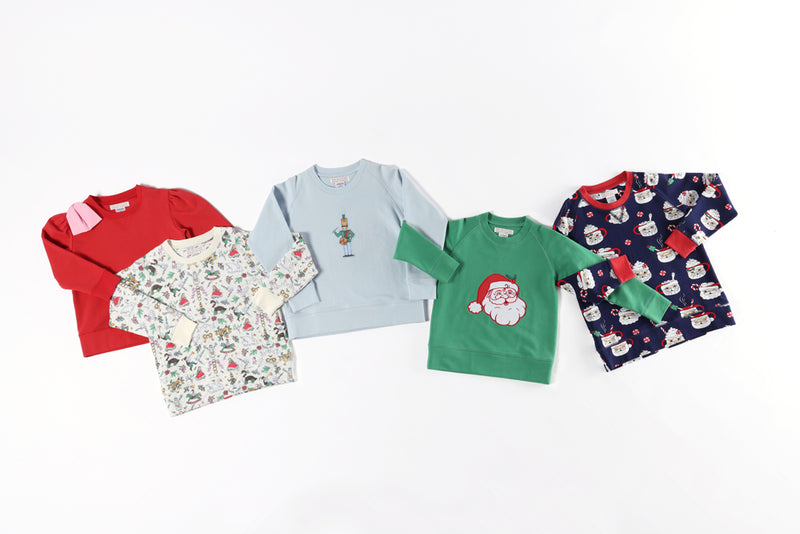 Five girls sweatshirts from The Beaufort Bonnet Company are arranged on a white background, showcasing festive designs such as Santa, snowmen, and colorful holiday patterns in red, green, blue, and multicolor. Included in the collection is the Puff Sleeve Cassidy Comfy Crewneck in Richmond Red with a Pier Party Pink Bow for added charm.