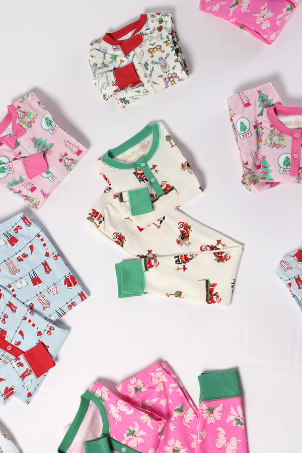 Several pairs of Fallon Footie Pajamas - Christmas Coloring Contest with Winter Park Pink featuring festive prints arranged on a white background.