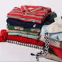 A neatly folded stack of The Beaufort Bonnet Company’s Long Sleeve Prim & Proper Polos & Onesie in Richmond Red, Kiawah Kelly Green, and Palmetto Pearl Stripe is displayed on a white background.