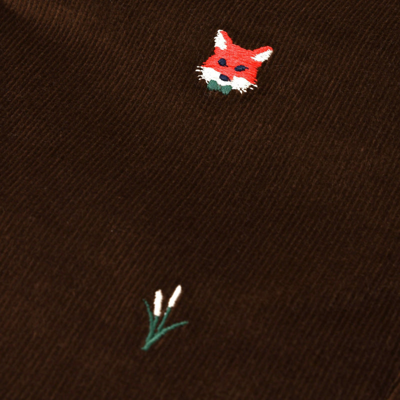 A close-up of The Beaufort Bonnet Company Critter Julia Jumper in Chelsea Chocolate corduroy, showcasing the fox embroidery—a red fox head alongside a delicate patch of white flowers with green stems.