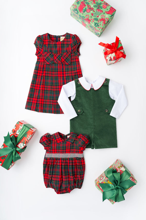 Three wrapped gifts surround a red Darcy Dress - Paces Mill Plaid by The Beaufort Bonnet Company, a coordinating plaid baby romper with bow details, and a green corduroy romper paired with a white shirt, all arranged on a white background.