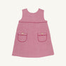 The Beaufort Bonnet Company’s Jill Jumper in Begley Berry Tweed is a sleeveless pink girls’ dress featuring two front pockets, each accented with a button and finished with dark pink trim. The classic, simple design is shown against a plain white background.