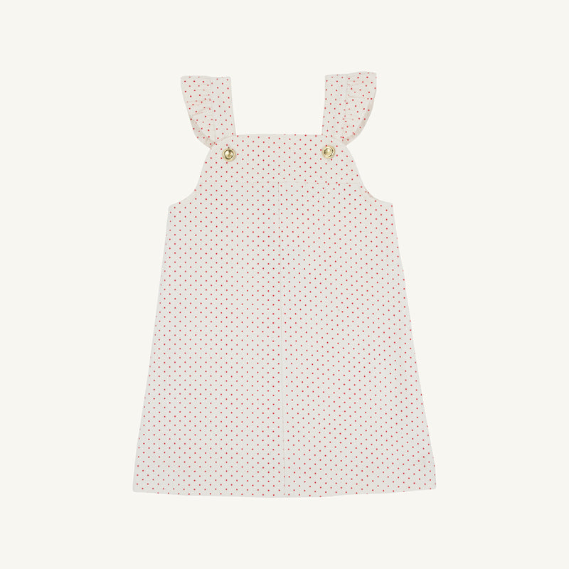 The Julia Jumper by The Beaufort Bonnet Company, shown laid flat on a white background, is a sleeveless pink corduroy dress featuring Richmond Red and Palmetto Pearl microdot polka dots, ruffled shoulder straps, and button details at the front.