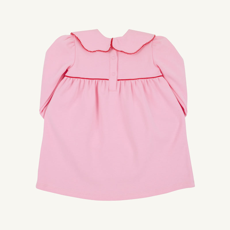 The Beaufort Bonnet Company’s Long Sleeve Maude’s Day Dress in Pier Party Pink with Richmond Red is a baby dress crafted from 100% Pima Cotton, featuring a scalloped collar, red trim, button closures on the upper back, and gentle gathering below the yoke.