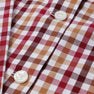Close-up of The Beaufort Bonnet Company’s Long Sleeve Peter Pan Collar Shirt & Onesie - Easton Pond Plaid, featuring a red, white, and beige checkered pattern with two white buttons.