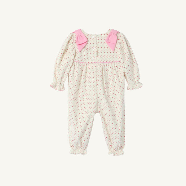 The Long Sleeve Ryleigh Romper by The Beaufort Bonnet Company features cream-colored Palmetto Pearl & Richmond Red microdot corduroy, long sleeves, delicate pink bows on the shoulders, pink piping across the chest, and ruffled cuffs at both the wrists and ankles. This charming winter outfit is displayed flat on a white background.